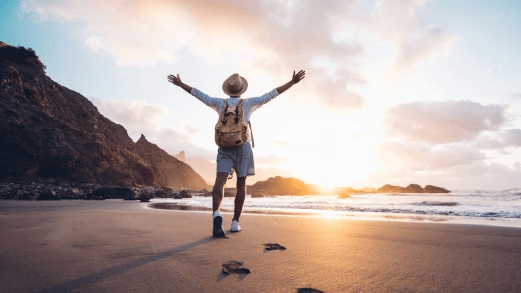 Man walking on a beach with raised hands